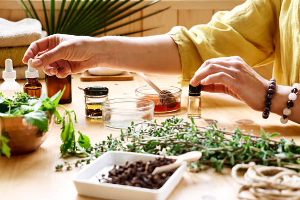 mujer prepara sesión de aromaterapia en la mesa con hierbas médicas difusores de aceite esencial, diferentes tipos de aceites y esencias. concepto de aromaterapia y medicina alternativa. remedios naturales. - naturopath fotografías e imágenes de stock