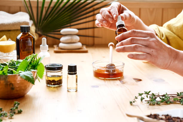 istock Woman prepares aromatherapy session at the table with essential oil diffuser medical herbs, different types of oils and essences. Aromatherapy and alternative medicine concept. Natural remedies. 1315042500