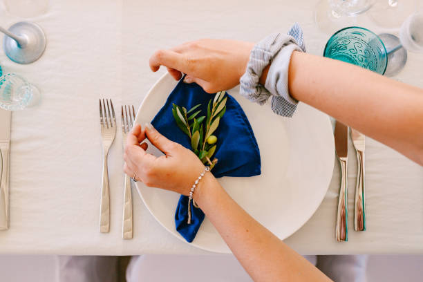Girl's hands wrap olive branches lying on a plate in a napkin