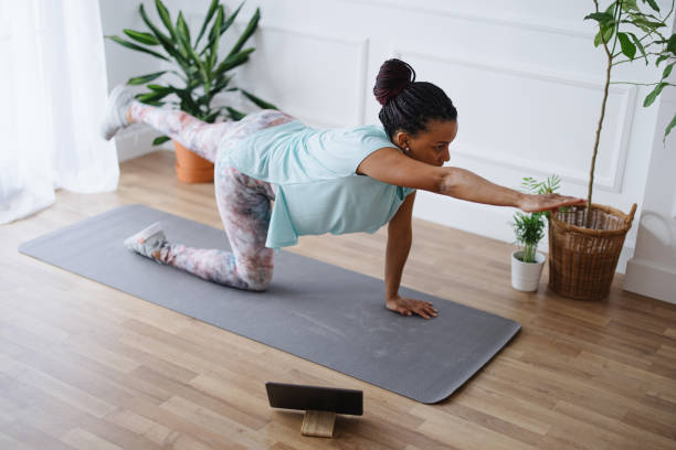 istock Woman practicing yoga at her home using digital tablet to watch exercises 1315049508