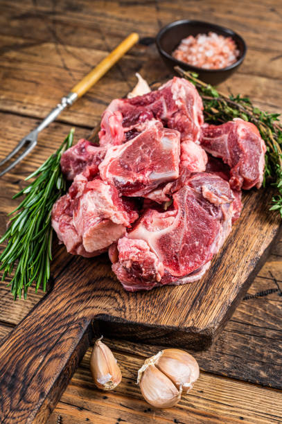 istock Raw beef  meat diced for stew with bone. wooden background. Top view 1315054273