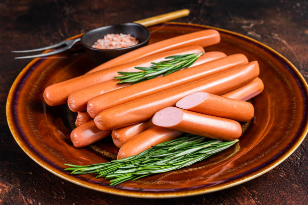 istock Frankfurter raw sausages in a rustic plate with herbs. Dark background. Top view 1315054947