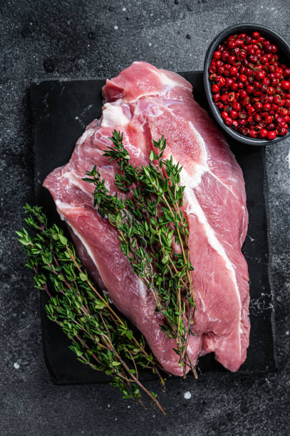 istock Raw pork shoulder meat cut on a marble board. Black background. Top view 1315062095