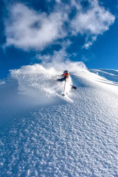 Photo of Skier descends steep mountain ridge through fresh powder snow