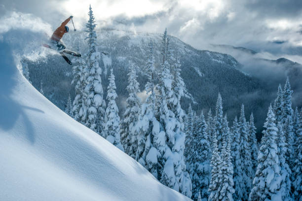 sciatore prende aria in una foresta coperta di neve in polvere profonda - skiing snow mountain canada foto e immagini stock