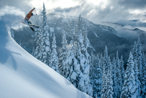 A young aggressive skier on an alpine slope demonstrates an extreme carving skiing style. He is skiing on morning perfectly groomed piste.