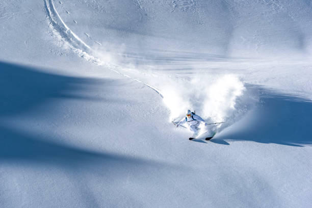 esquiador desciende escarpada cresta de montaña a través de nieve polvo fresca - skiing snow skiing helmet fun fotografías e imágenes de stock