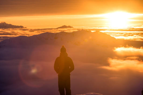 Man looks towards mountains illuminated by morning light