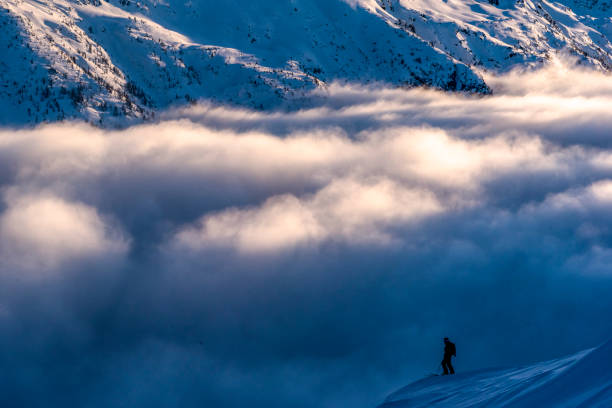 Ski mountaineer pauses on mountain ridge at sunrise