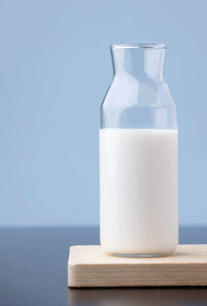 istock transparent glass milk bottle, on wood, blue background 1315070830