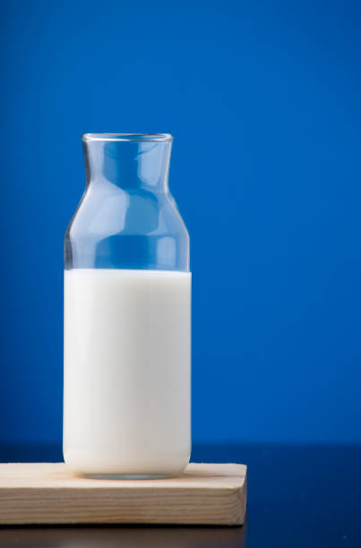 istock transparent glass milk bottle, on wood, blue background 1315070854