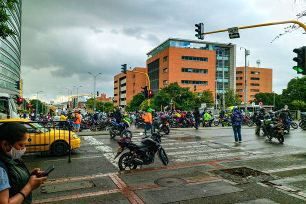 Bogota, Colombia - A Larger Number Of Bikers Block Normal Traffic In A Protest In The Capital City Against The Tax Reform Bill Due To Come Up Shortly Before The Colombian Parliament. Bogota, Colombia - April 28, 2021: A group of bikers block the intersection where Calle 116 meets Carrera Séptima in front of Hacienda Santa Barbara, in the Colombian Capital City in protest against the Tax Reform Bill Due to come up before the Colombian Parliament shortly. Traffic was blocked for a short period of time at vrious points of the city. This one probably blocked this point of an important arterial road of the City for about 20 minutes. The sky is overcast. There have been a few showers. More rain is expected. Horizontal format. inconvenience photos stock pictures, royalty-free photos & images