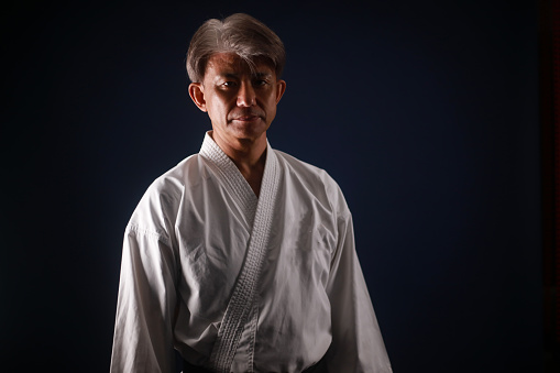 Portrait of a senior Japanese woman captures her martial arts journey, as she stands proudly in her karate uniform, an inspiration to all who train with her.