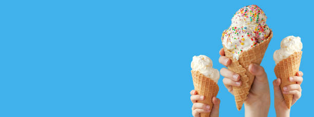 istock Hands holding a vanilla ice cream cone on blue background. Banner. 1315108851