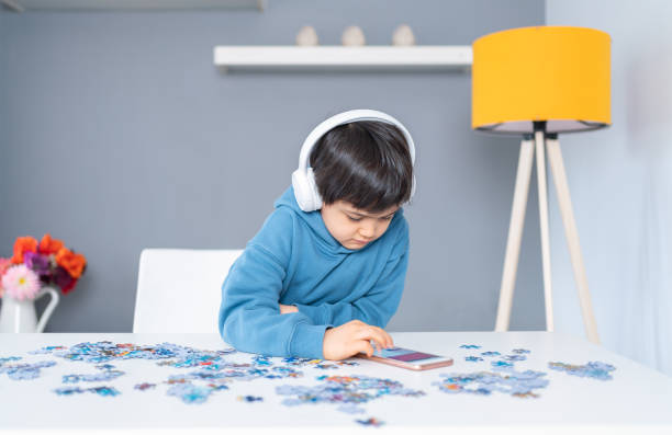 istock Little cute boy using  smartphone. Child playing puzzle at home 1315113077
