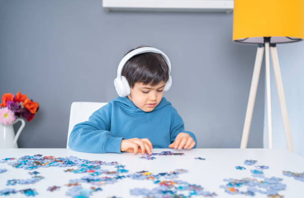 istock Little cute boy with headphone playing puzzle at home. Kid assembling a jigsaw puzzle 1315113128