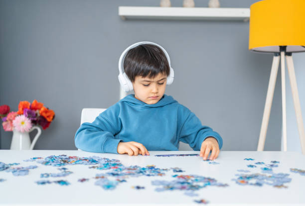 istock Little cute boy with headphone playing puzzle at home. Kid assembling a jigsaw puzzle 1315113131