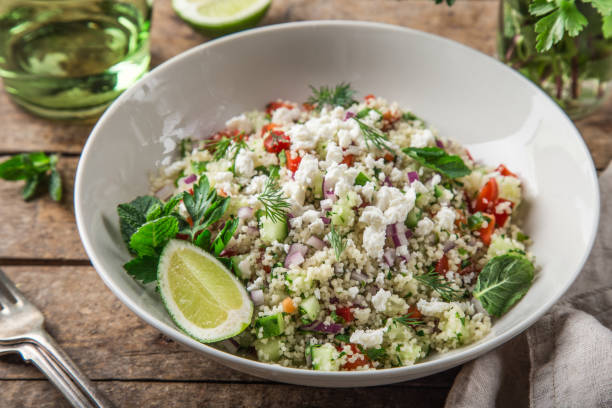 couscous and vegetables salad with feta cheese in white bowl couscous and vegetables salad with feta cheese in white bowl, wooden background, top view bulgur wheat stock pictures, royalty-free photos & images