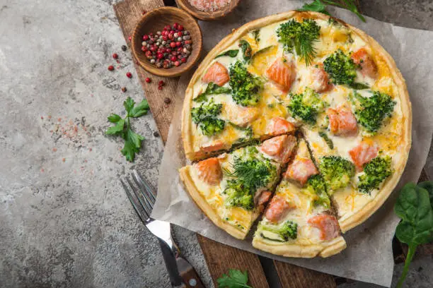 smoked salmon, broccoli and spinach quiche tart, top view, copy space