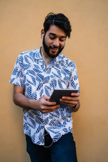 istock Latin man using his digital tablet with earphones. 1315120982