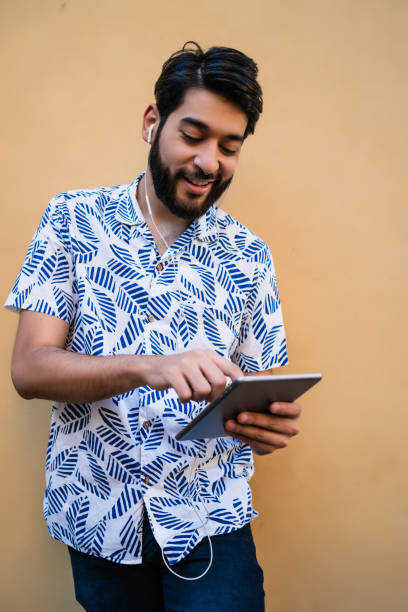 istock Latin man using his digital tablet with earphones. 1315120984