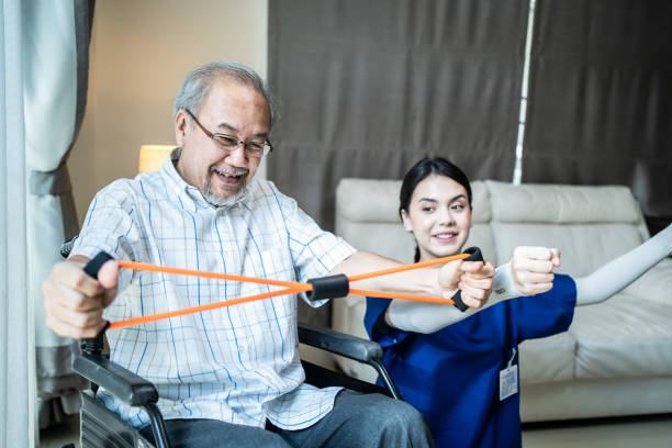 istock Asian Disabled senior elderly man on wheelchair doing physiotherapist with support from therapist nurse. Older handicapped man using resistance stretch band exercise for patient in home nursing care. 1315122795