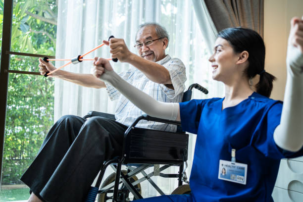 istock Asian Disabled senior elderly man on wheelchair doing physiotherapist with support from therapist nurse. Older handicapped man using resistance stretch band exercise for patient in home nursing care. 1315122800