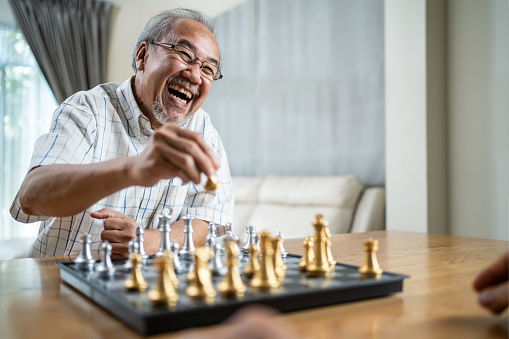 Retrato de ancianos asiáticos mayores pasan tiempo libre, se quedan en casa después de la jubilación. Feliz sonriente Anciano disfrutar de la actividad en casa jugar juego de ajedrez con amigo. Hospital Healthcare y concepto médico photo