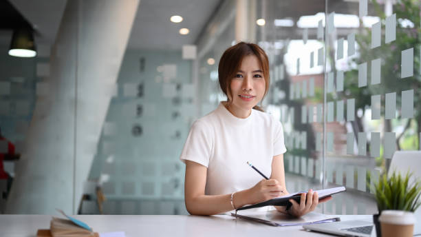 istock Successful businesswoman holding notebook and smiling to camera while sitting in modern workplace. 1315124455