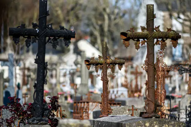 Photo of An old rusty Catholic cross in a cemetery in France.