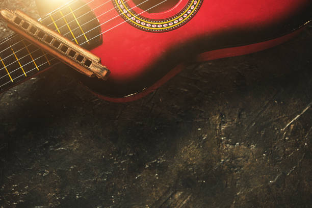 istock Old harmonica and a red guitar on a dark abstract background with sunlight. Musical instrument. 1315125168