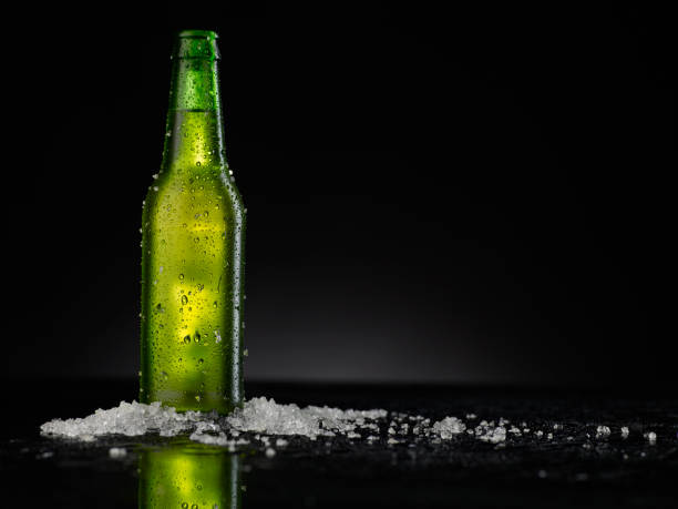 istock Ice Cold Green Beer Bottle Covered with water drops - condensation. Blank for drink beverage product design mock-up.  Standing on black table with dark - black background. 1315126391