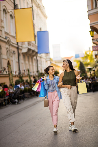 Two women on street carrying shopping bags.