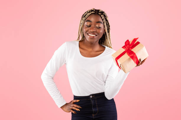 istock Happy black woman holding present box and thinking 1315128292