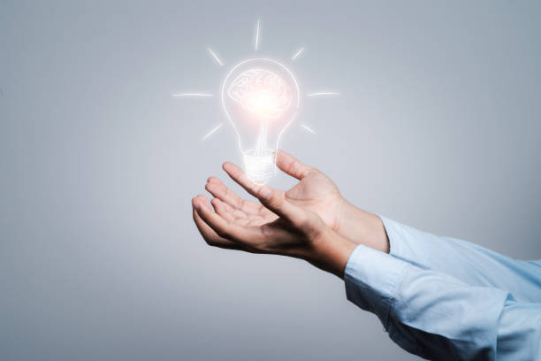 istock Two hands holding the drawing light bulb that is illuminating. Creative protecting patents and ideas concept. 1315131203