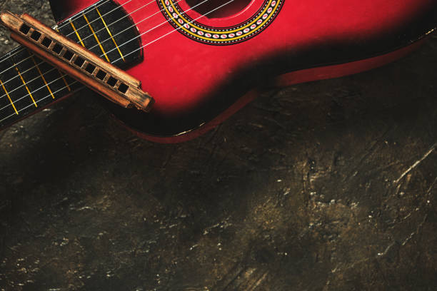 istock Old harmonica and a red guitar on a dark abstract background. Musical instrument. 1315131900
