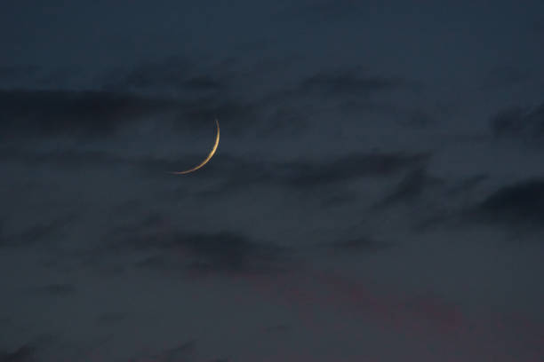 crescent moon with thin clouds on the evening sky stock photo
