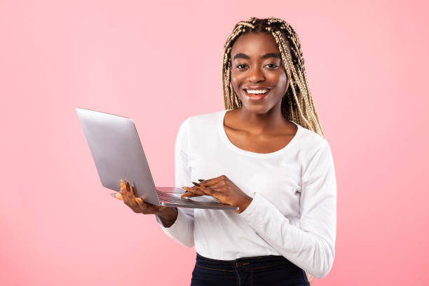 istock Smiling young black lady holding and using laptop at studio 1315136255
