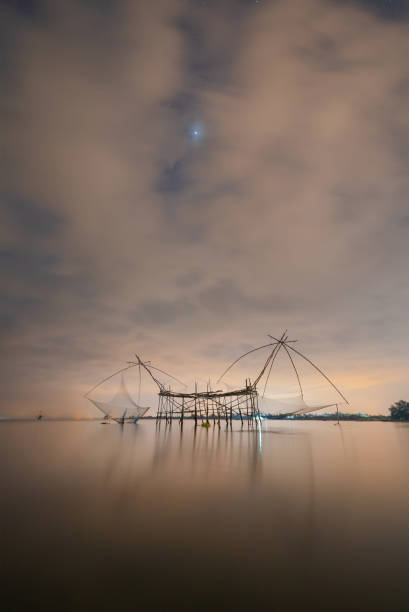 Local fishing trap net in canel, lake or river at night. Nature landscape fisheries and fishing tools lifestyle at Pak Pha, Phattalung, Thailand. Aquaculture farming. Local fishing trap net in canel, lake or river at night. Nature landscape fisheries and fishing tools lifestyle at Pak Pha, Phattalung, Thailand. Aquaculture farming. phatthalung province stock pictures, royalty-free photos & images