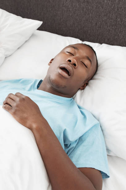 istock Tired man sleeping on bed with snore face at cozy home 1315138315