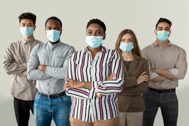 istock Multicultural businesspeople in masks standing in office with folded arms 1315139441