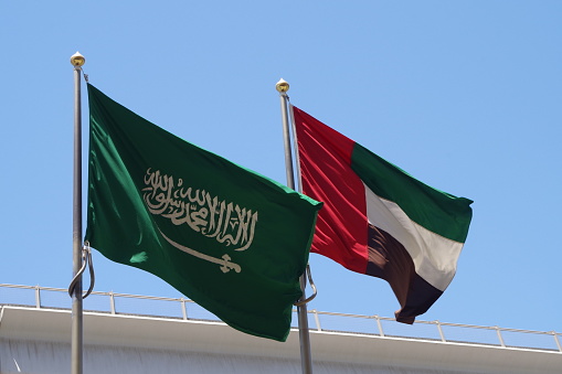 Banderas nacionales de Arabia Saudita y Emiratos Árabes Unidos ondeando en asta bandera en el cielo.  Las naciones más influyentes del Golfo Árabe. photo
