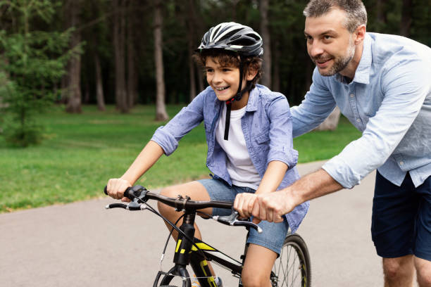 istock Boy learning how to ride bicycle with his happy dad 1315140952