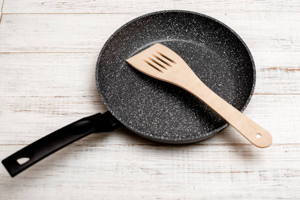 istock Frying pan with non-stick ceramic coating and spatula on a white wooden background. Cooking without sticking or oil. 1315141585