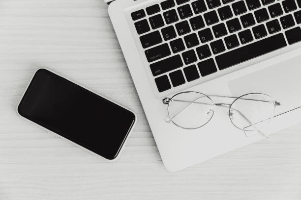 istock laptop computer on the desk with smartphone and glasses top view monotone for minimal business flat lay picture. 1315142464