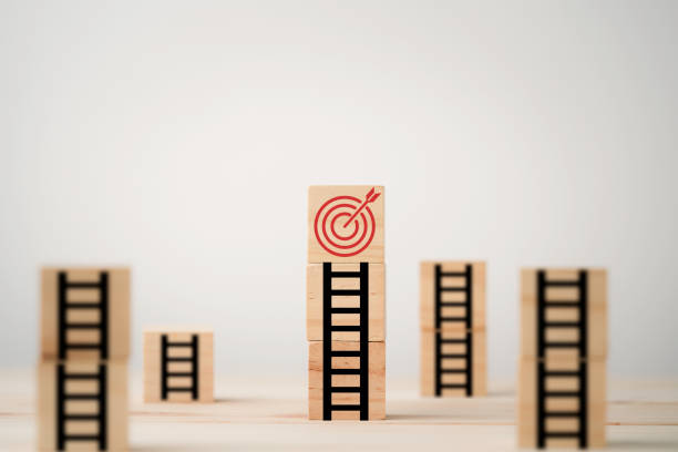 istock Target board on the top of ladder which print screen on wooden cube block, setup challenge achievement objective in business and life concept. 1315143462