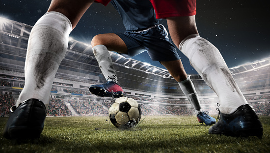 Dribbling. Close-up two professional football or soccer players in action at stadium in flashlights. Team sports event. Moment of attacking. Concept of sport, competition, action, motion. Rear view