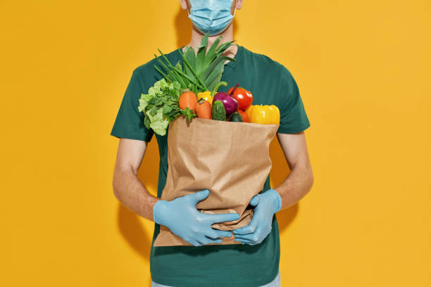 istock Young caucasian courier holding packet with fresh vegetables 1315146253