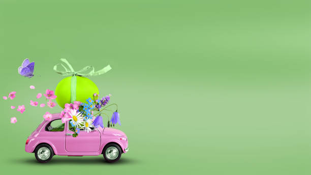 Pink toy car carrying an easter egg and wild flowers on the roof on a green background. Pink retro toy car carrying an easter egg and flowers bunch on a green background. Copy space toy vehicle stock pictures, royalty-free photos & images