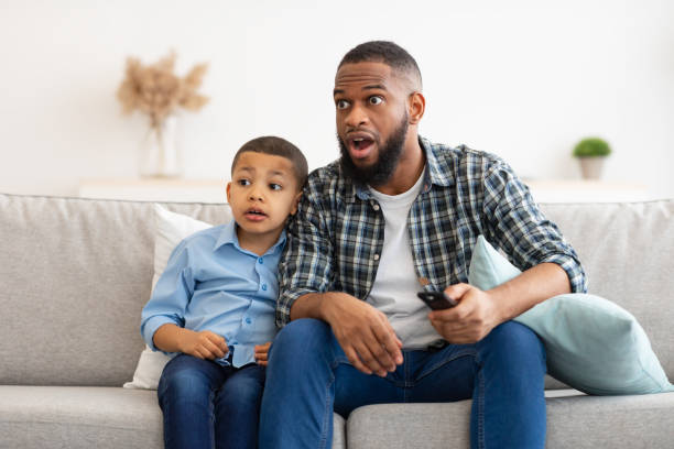 istock Confused Dad And Son Watching TV, Switching Questionable Content Indoor 1315148685